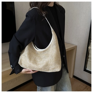 Detail of woven straw hobo bag with white leather straps shown on model in studio