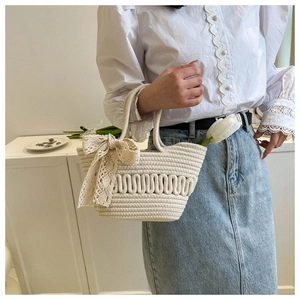 Detail einer beigen gewebten Handtasche mit Spitzenschleife und Blumendekor im sanften Look