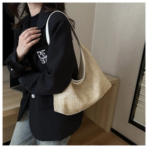 Detail of hand-woven straw hobo bag with white leather trim in an office setting