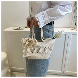 Detail einer gewebten weißen Handtasche mit Wellenstrukturen und Spitzen-Schleife