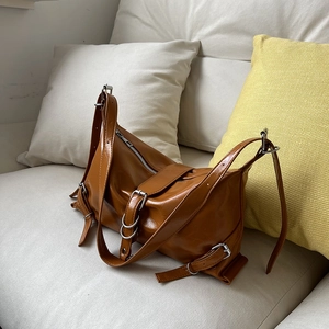 Sac sous le bras en cuir marron rétro avec boucles réglables sur un canapé beige
