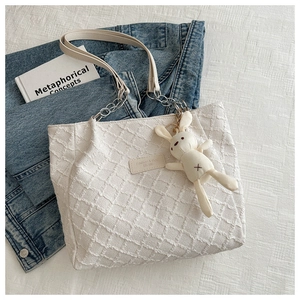 Détail du sac cabas en toile matelassée blanche avec chaîne argentée et lapin en peluche
