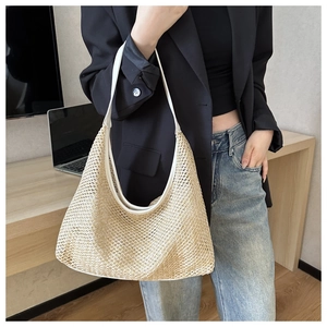 Large capacity straw woven shoulder bag shown on model in a casual summer indoor setting