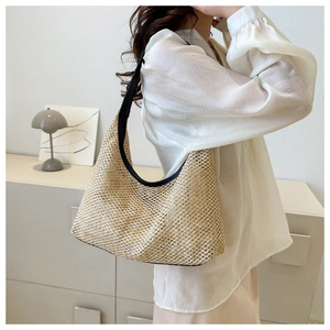 Detail of hobo straw shoulder bag with black leather strap on a minimalist model