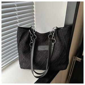 Gros plan du sac cabas en toile texturée avec bandoulière chaîne et étiquette cuir