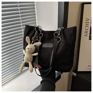 Détail du sac cabas noir texturé avec bandoulière chaîne et pendentif lapin