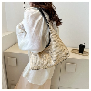 Detail of woven straw tote bag featuring black leather trim and soft summer texture