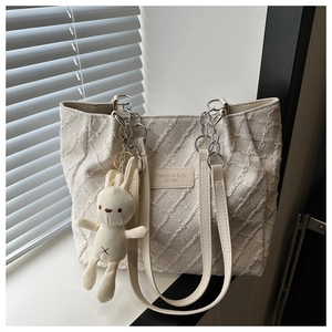Détail du sac cabas en tweed blanc avec texture matelassée, chaîne argentée et lapin