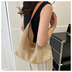 Detail of hand-woven straw tote bag with brown leather shoulder strap for summer style