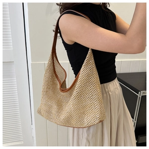 Detail of handwoven straw tote bag with brown leather handles and hollow texture