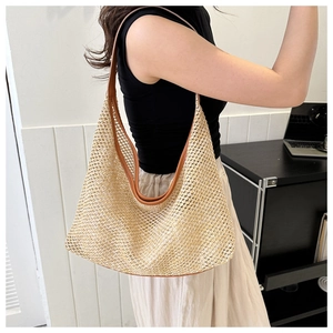 Detail of the woven mesh texture and brown leather strap on the large straw hobo bag