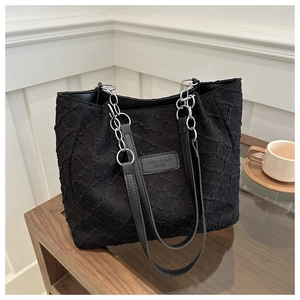Détail du sac cabas noir avec texture gaufrée et bandoulière en chaîne argentée