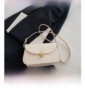 Détail d'un sac besace crème avec boucle en métal doré et texture de cuir lisse élégante
