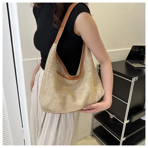 Detail of beige straw tote bag with brown faux leather straps shown on a model