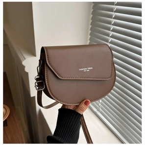 Détail du sac besace marron foncé avec inscription tendance et boucle en métal