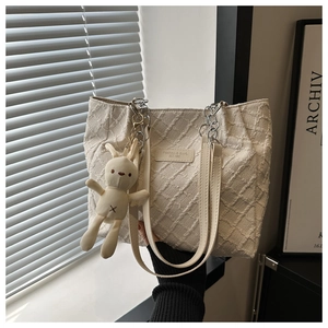 Détail du sac cabas tissé blanc cassé avec chaîne en métal et breloque lapin mignon