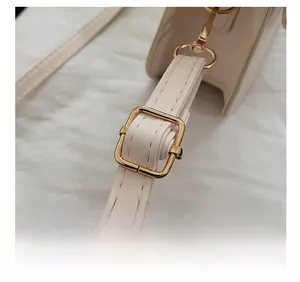 Détail d'une bandoulière réglable en similicuir beige avec boucle en métal doré