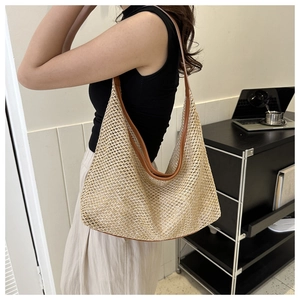 Detail view of woven straw tote bag with brown leather straps and hollow round pattern