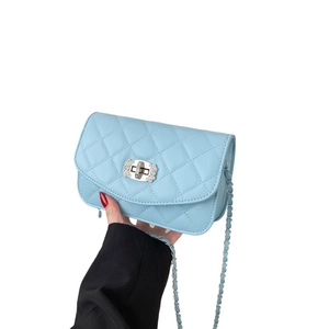 Light blue quilted leather crossbody bag with crystal buckle and chain strap shown in hand