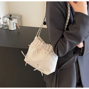 Détail du sac seau plissé blanc crème avec nœuds et bandoulière en chaîne argentée
