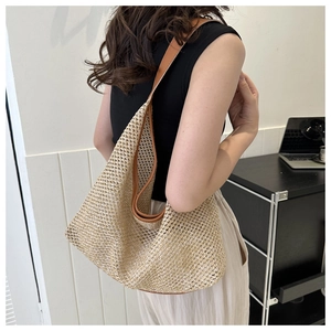 Detailed view of straw woven tote bag with brown leather trim for summer commute