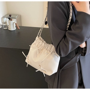 Détail du sac seau plissé blanc crème avec nœuds décoratifs et bandoulière chaîne