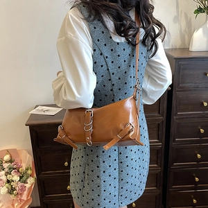 Sac à bandoulière en cuir marron avec boucles argentées vintage dans un décor cosy