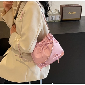 Detail of pink pleated bucket bag with decorative bows and silver chain strap