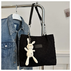 Détail du sac cabas noir texturé avec pendentif lapin et bandoulière en chaîne