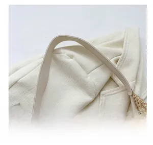 Detail view of woven straw tote bag featuring a premium off-white leather shoulder strap