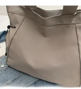 Close-up of taupe nylon tote bag with drawstring detail on casual denim fabric