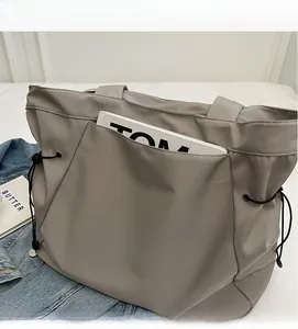 Close-up of grey large capacity tote bag featuring functional front pocket and drawstring side