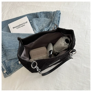 Détails de l'intérieur spacieux du sac cabas en toile noire avec des articles essentiels