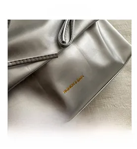 Detail of silver metallic leather texture with gold Fashion & Bags logo lettering