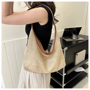Detail of large woven straw tote bag with brown leather trim and shoulder strap for summer