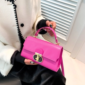 Rose pink leather crossbody bag with gold buckle clasp held by model in tweed jacket
