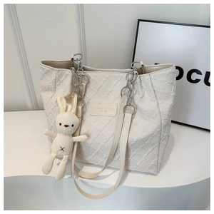 Détail du cabas en toile blanc cassé avec logo en cuir et breloque lapin en peluche
