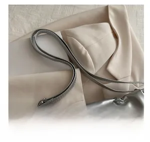 Close-up of metallic silver tote bag with crinkled texture on a beige blazer