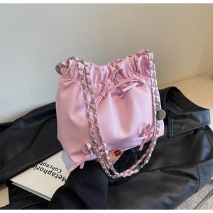 Gros plan du sac seau rose plissé avec nœuds et bandoulière en chaîne argentée