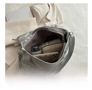 Spacious silver metallic tote interior holding a wallet, phone, and bottle