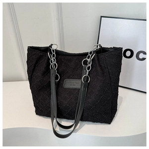 Détail du sac cabas noir texturé avec chaîne en métal argenté et patch logo