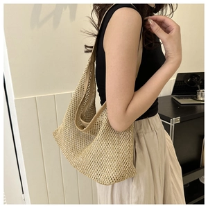 Woman wearing a large woven straw shoulder bag with mesh design for summer vacation style
