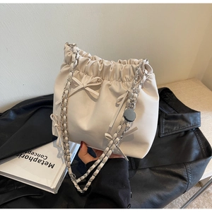 Détail du sac seau plissé crème avec petits nœuds et bandoulière en chaîne argent