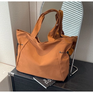 Close-up of caramel nylon tote bag with side drawstrings in a lifestyle setting