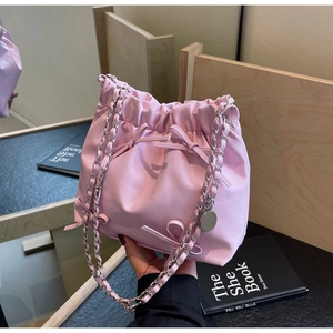 Détail de sac seau rose plissé avec nœuds décoratifs et bandoulière en chaîne argent