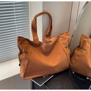 Detail of caramel tote bag showing nylon texture and side drawstring adjustment design