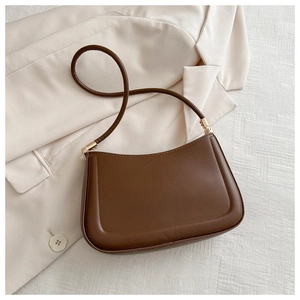 Detailed close-up of dark brown leather underarm bag with gold metal hardware on blazer