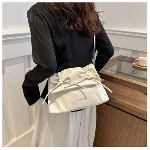 Detail of soft cream PU leather crossbody bag with pleated texture and side bow ties