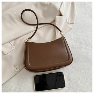 Detail view of small dark brown shoulder bag capacity compared with a smartphone