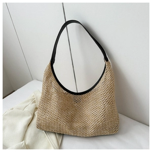 Detailed texture of straw hobo bag with black leather strap against a minimalist blazer